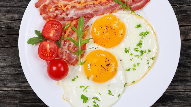 breakfast platter with eggs, bacon, and tomatoes
