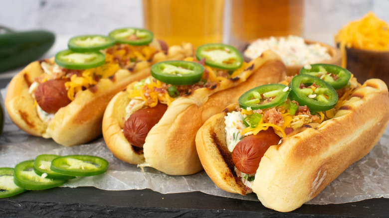 Three jalapeño popper hot dogs on parchment paper
