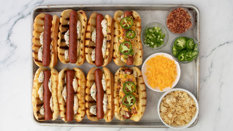 Hot dogs with various jalapeño popper toppings in sheet pan