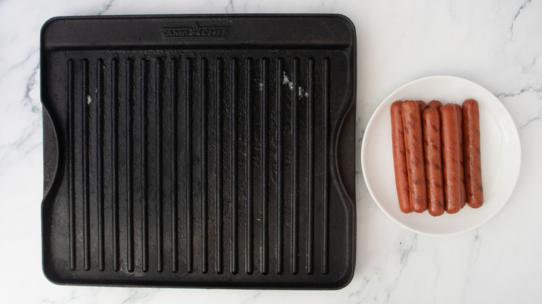 Grill pan next to hot dogs on plate