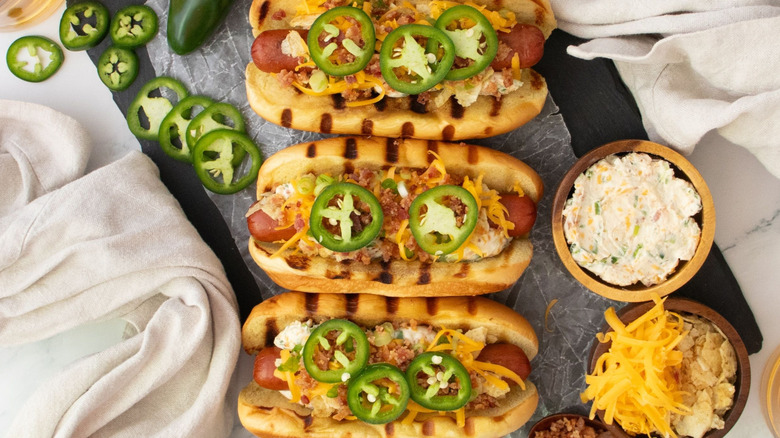 Jalapeño popper hot dogs next to bowl of cream cheese and shredded cheese