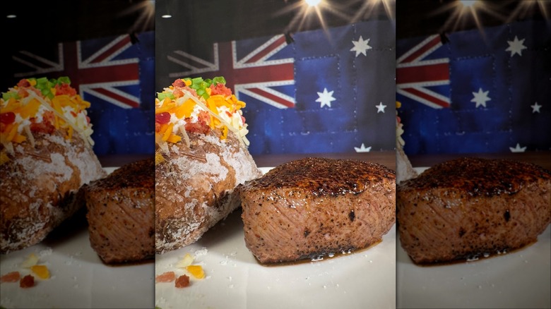 Steak and loaded baked potato on plate in front of Australian flag backdrop