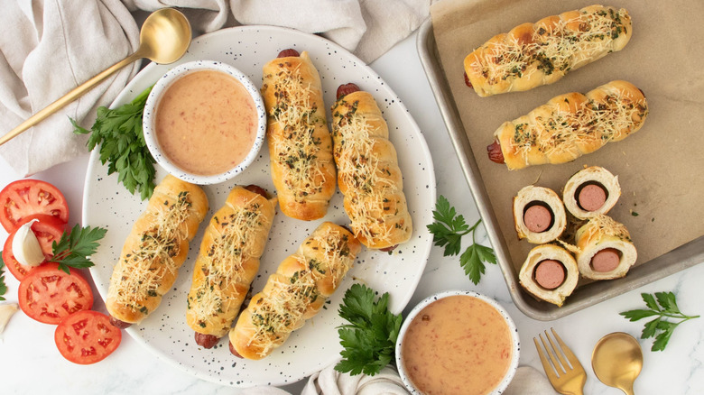 Garlic bread wrapped hot dogs on plate with sauce