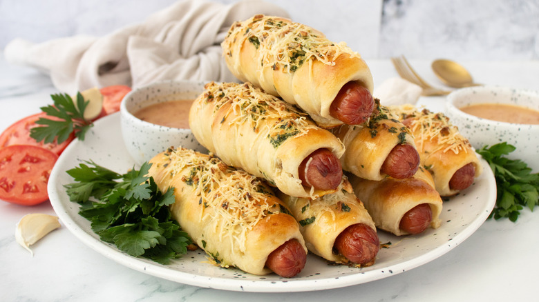 Garlic bread wrapped hot dogs stacked on plate