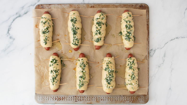 Dough-wrapped hot dogs topped with herby garlic butter
