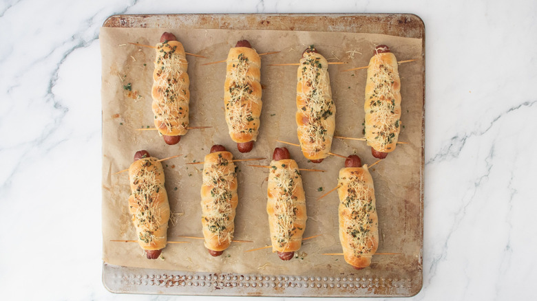 Baked garlic bread-wrapped hot dogs on baking sheet