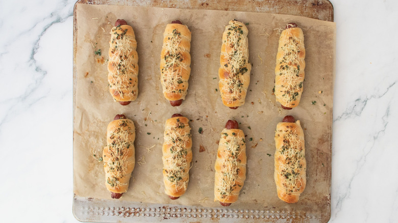 Garlic bread wrapped hot dogs on baking sheet