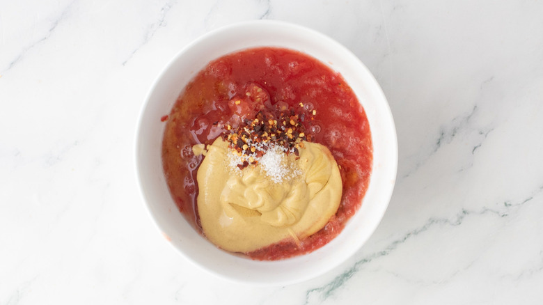 Grated tomato, mustard, and red pepper flakes in bowl