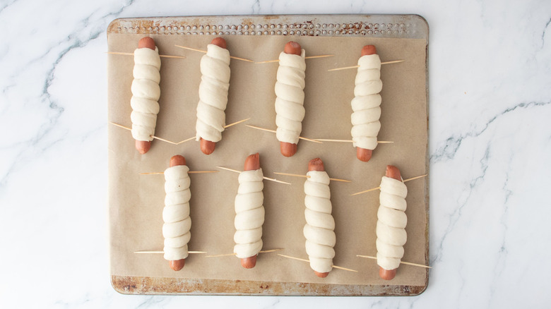 Dough-wrapped hot dogs on baking sheet