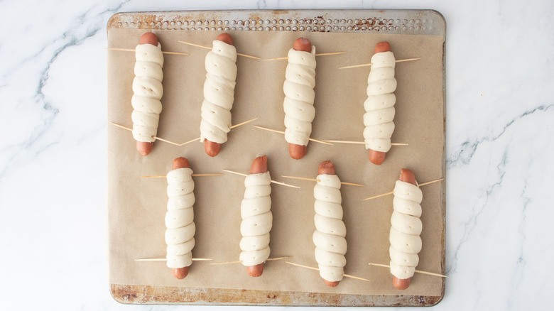 Dough-wrapped hot dogs on baking sheet
