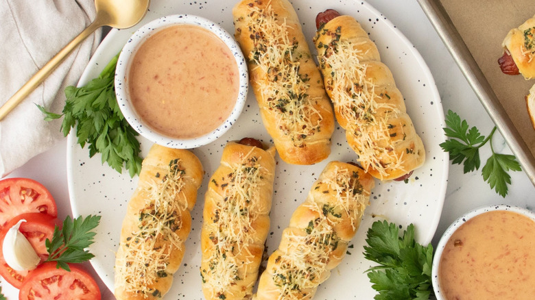 Garlic bread wrapped hot dogs on plate with sauce