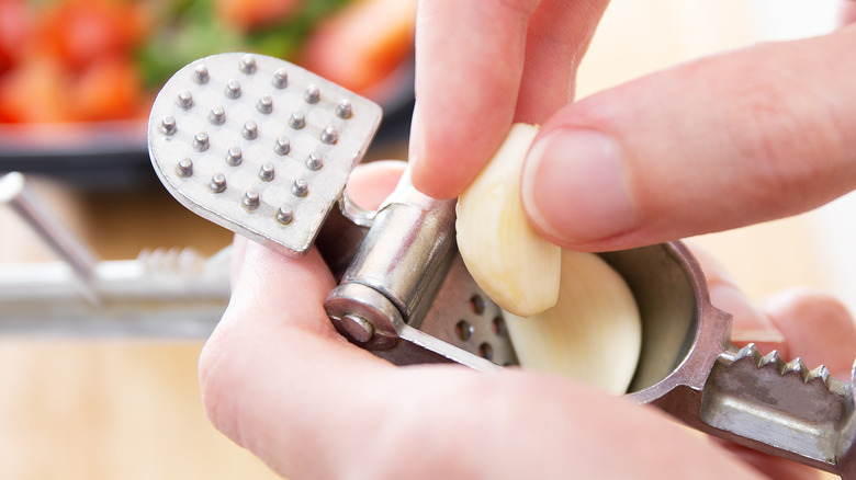 Person putting garlic in garlic press