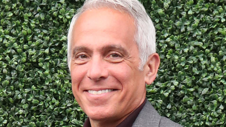 Geoffrey Zakarian smiling in front of row of leaves