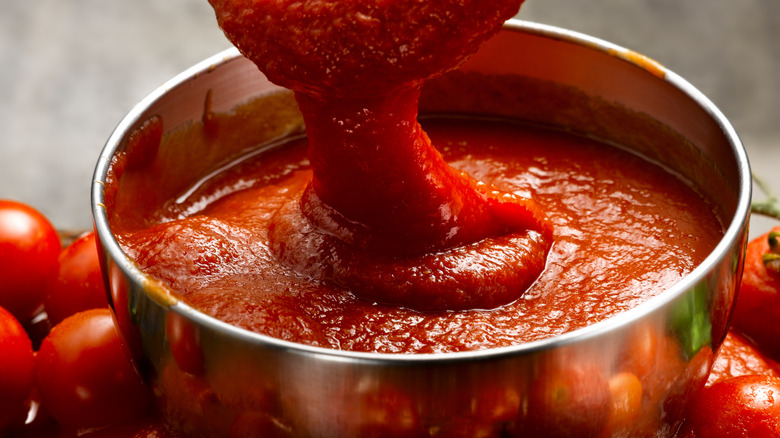 A bowl of tomato sauce next to fresh tomatoes