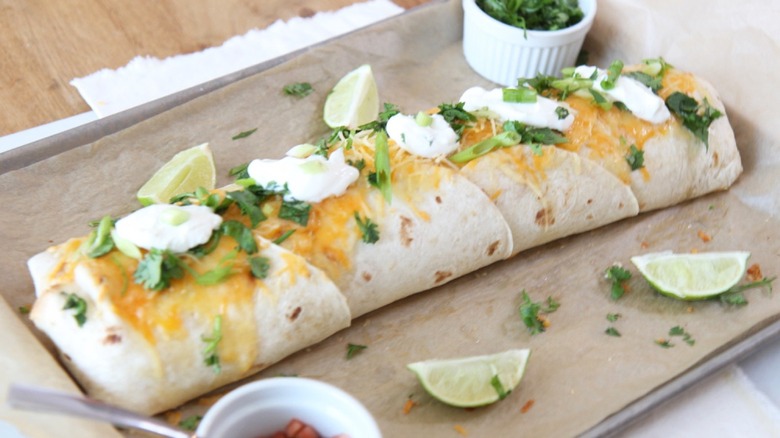 Giant burrito on tray with lime and sour cream