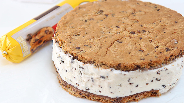 giant chocolate chip cookie ice cream sandwich beside a roll of chocolate chip cookie dough