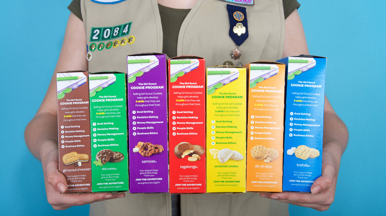 A girl scout holding boxes of girl scout cookies