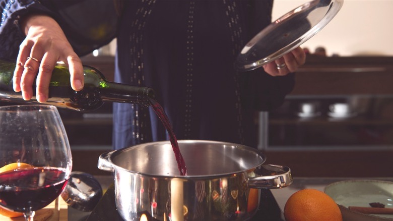 Person pouring red wine into a pot