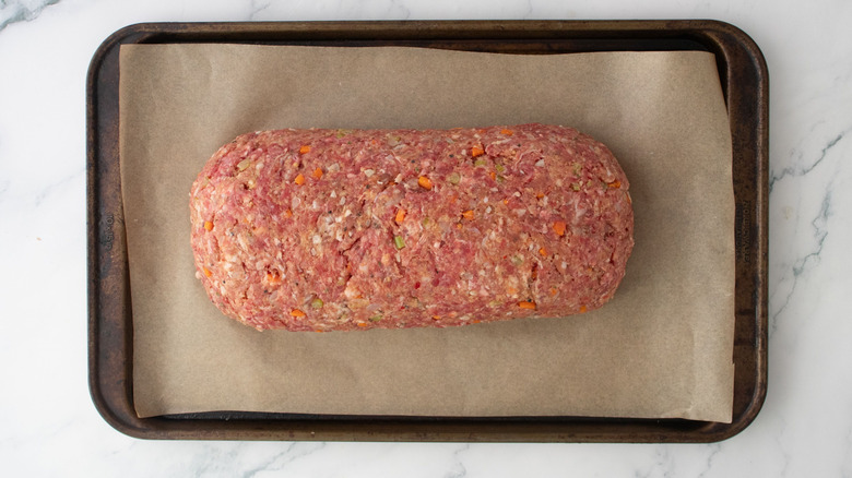 Meatloaf sitting on parchment lined baking sheet