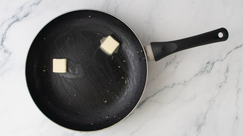Pats of butter melting in skillet