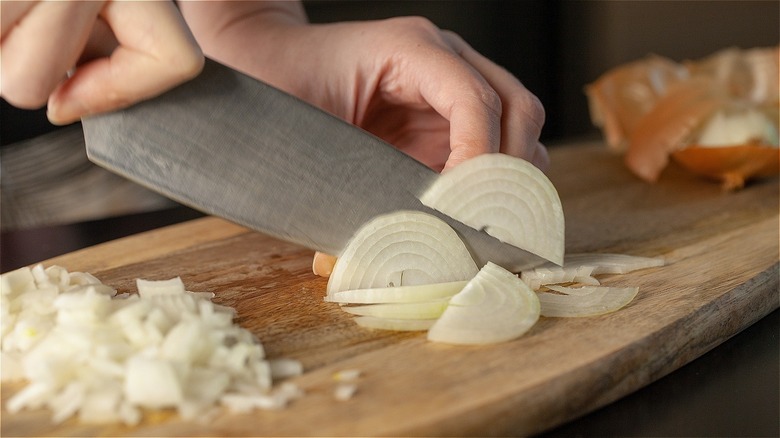 hands chopping onion with knife