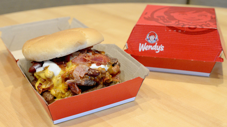 Wendy's cheeseburger topped with chili and bacon in box.