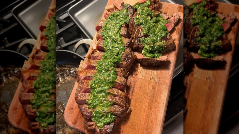Salmoriglio-topped sliced steak on a wooden cutting board