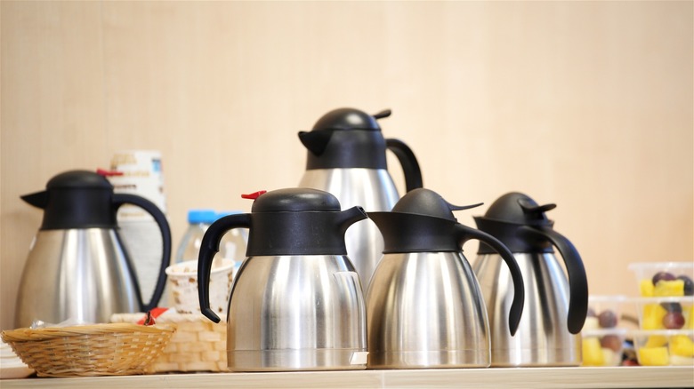 Multiple thermal carafes on a table for coffee.
