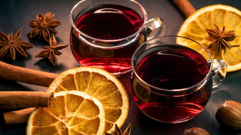 two cups with red wine, oranges, and spices