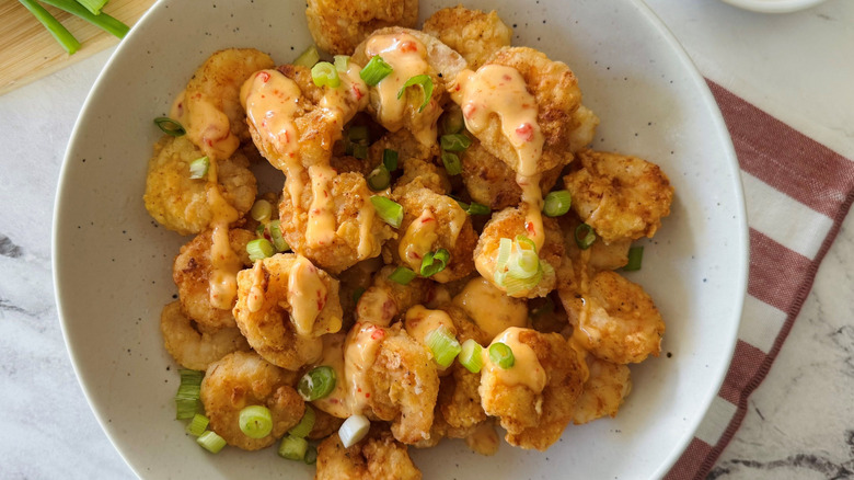 Fried shrimp in bowl topped with chili mayo sauce