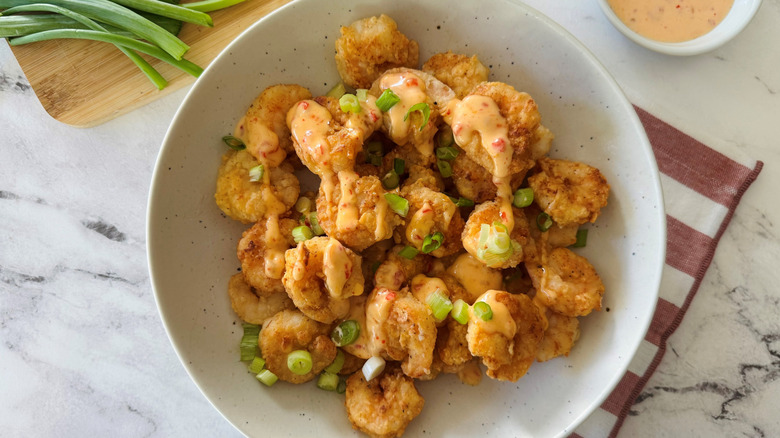 Bowl of fried shrimp drizzled with chili mayonnaise sauce