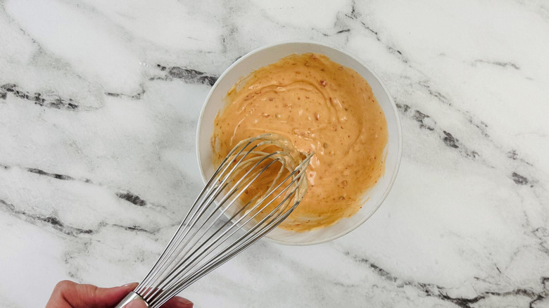Sweet chili mayo sauce in bowl with whisk