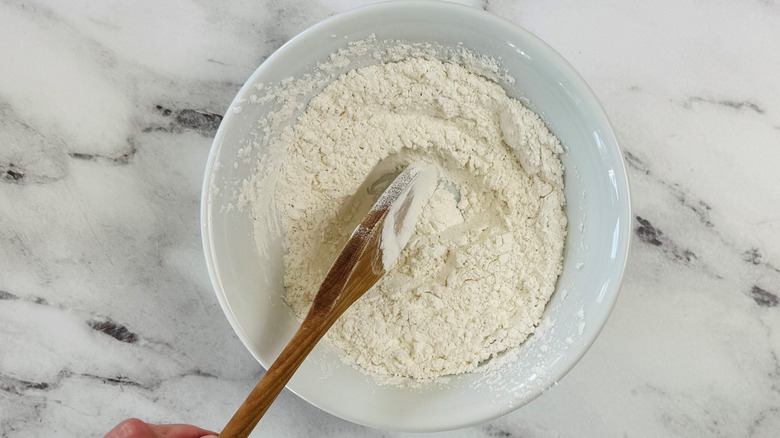 Wooden spatula mixing flour in bowl
