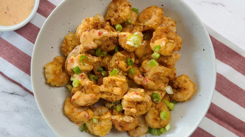 Fried shrimp in bowl drizzled with chili mayo sauce