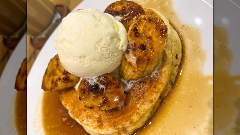 Syrup-covered pancakes with caramelized bananas and a scoop of vanilla ice cream