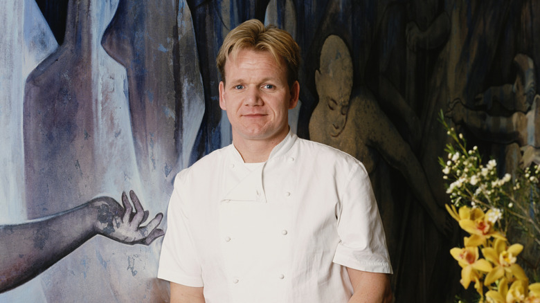 Gordon Ramsay in chef's whites standing in front of painting