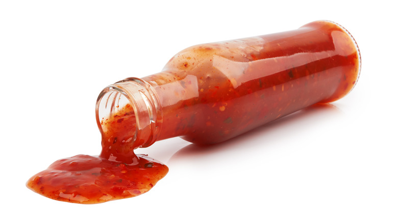a glass bottle of hot sauce pouring out