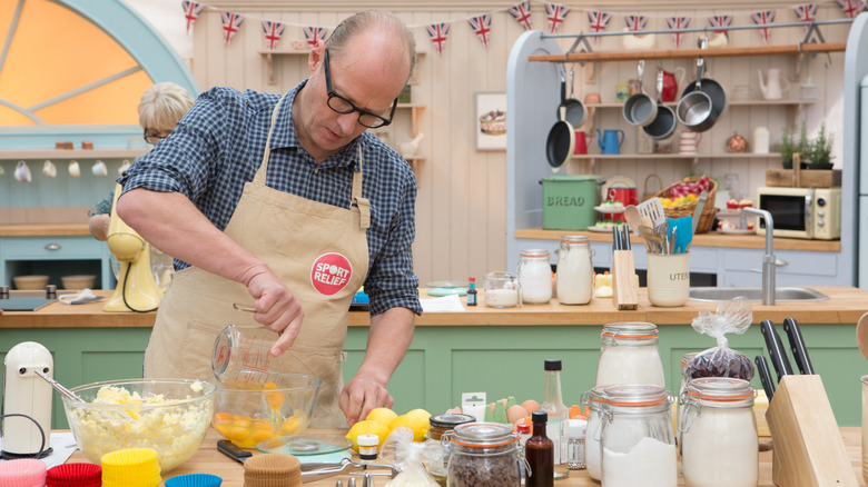 Ade Edmondson pours eggs in kitchen