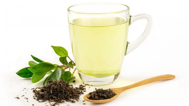 A cup of green tea with tea leaves 