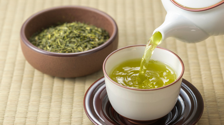 Pouring green tea into a mug