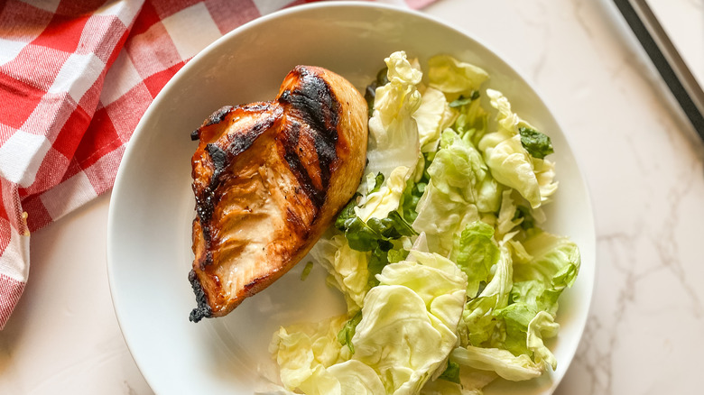 A serving of grilled wedding chicken on a plate with salad