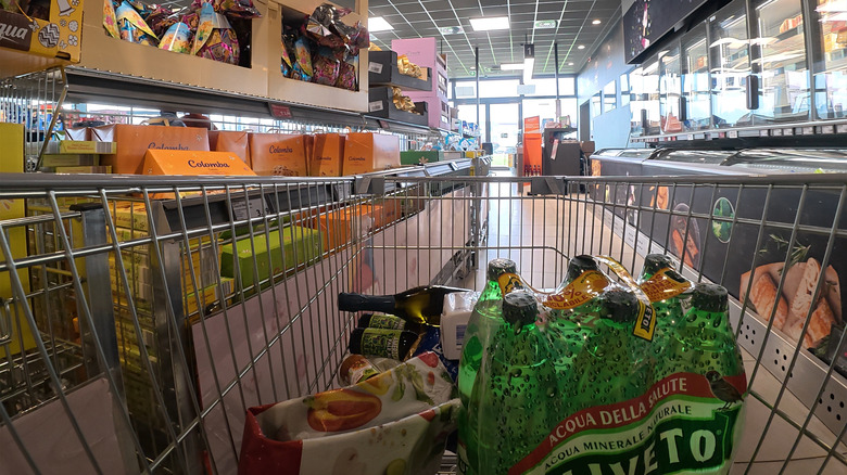 Cart full of groceries pointed down the aisle inside Aldi