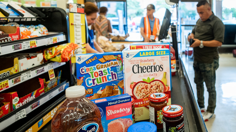 Grocery items on a checkout counter at a Kroger grocery store while a customer pays
