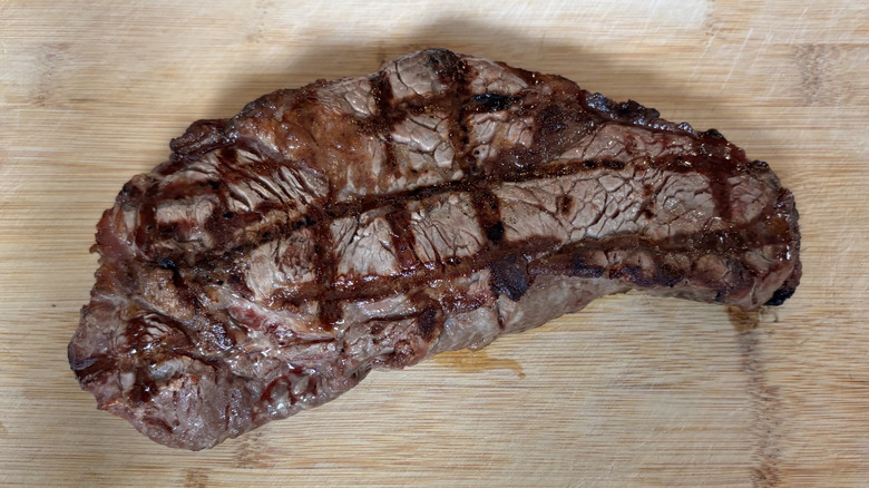 NY Strip steak with only a slight curve after grilling on a cutting board