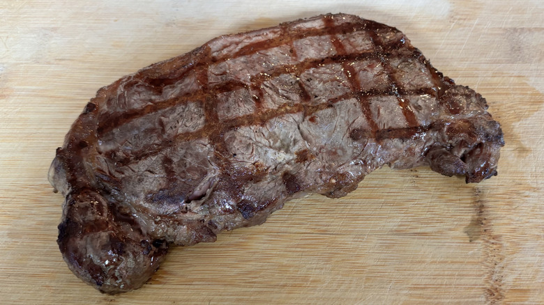 Thick NY strip with grill marks on cutting board