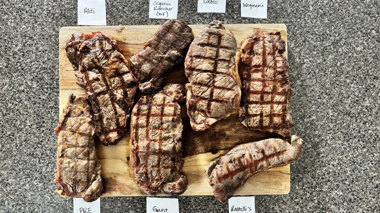 Grilled steaks resting on cutting board with labels from grocery stores
