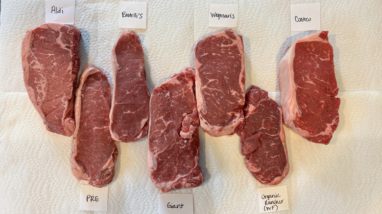 Raw NY strip steaks laid on paper towels and labeled by grocery store