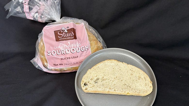 Bagged loaf of Stan's Sourdough next to slice of bread on gray plate