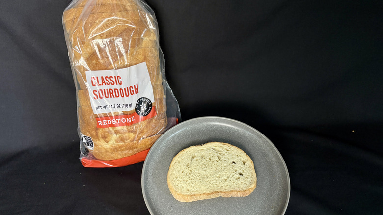 Bagged loaf of Redstone Sourdough next to slice of bread on gray plate