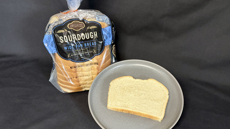 Bagged loaf of Private Selection Sourdough next to slice of bread on gray plate